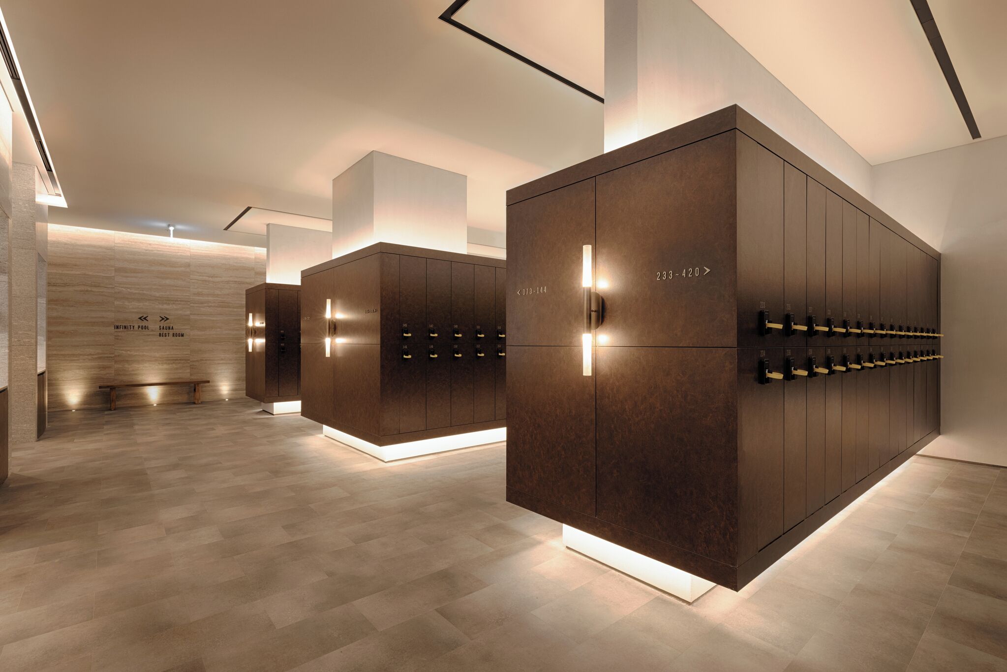 A modern hotel lobby with a central seating area, a large wooden wall, and a row of lockers.