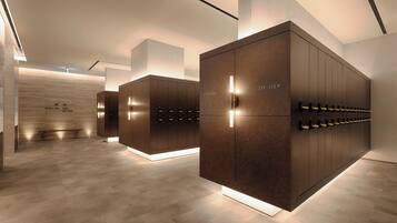 A modern hotel lobby with a central seating area, a large wooden wall, and a row of lockers.