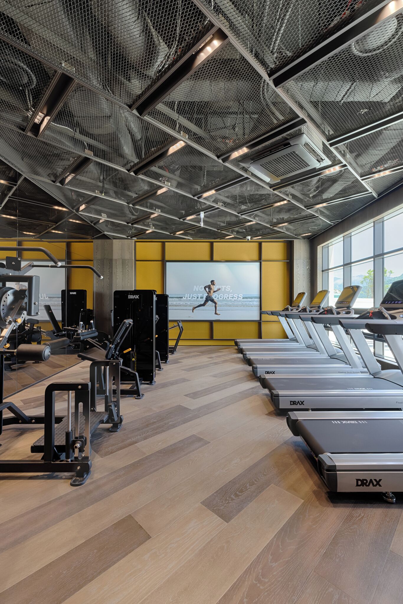 Ein Fitnessstudio mit Laufbändern, Krafttrainingsgeräten und einem motivierenden Plakat an der Wand.