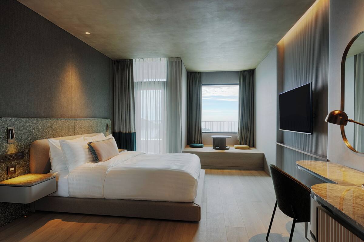 A modern hotel room with a large bed, a desk, and a TV.