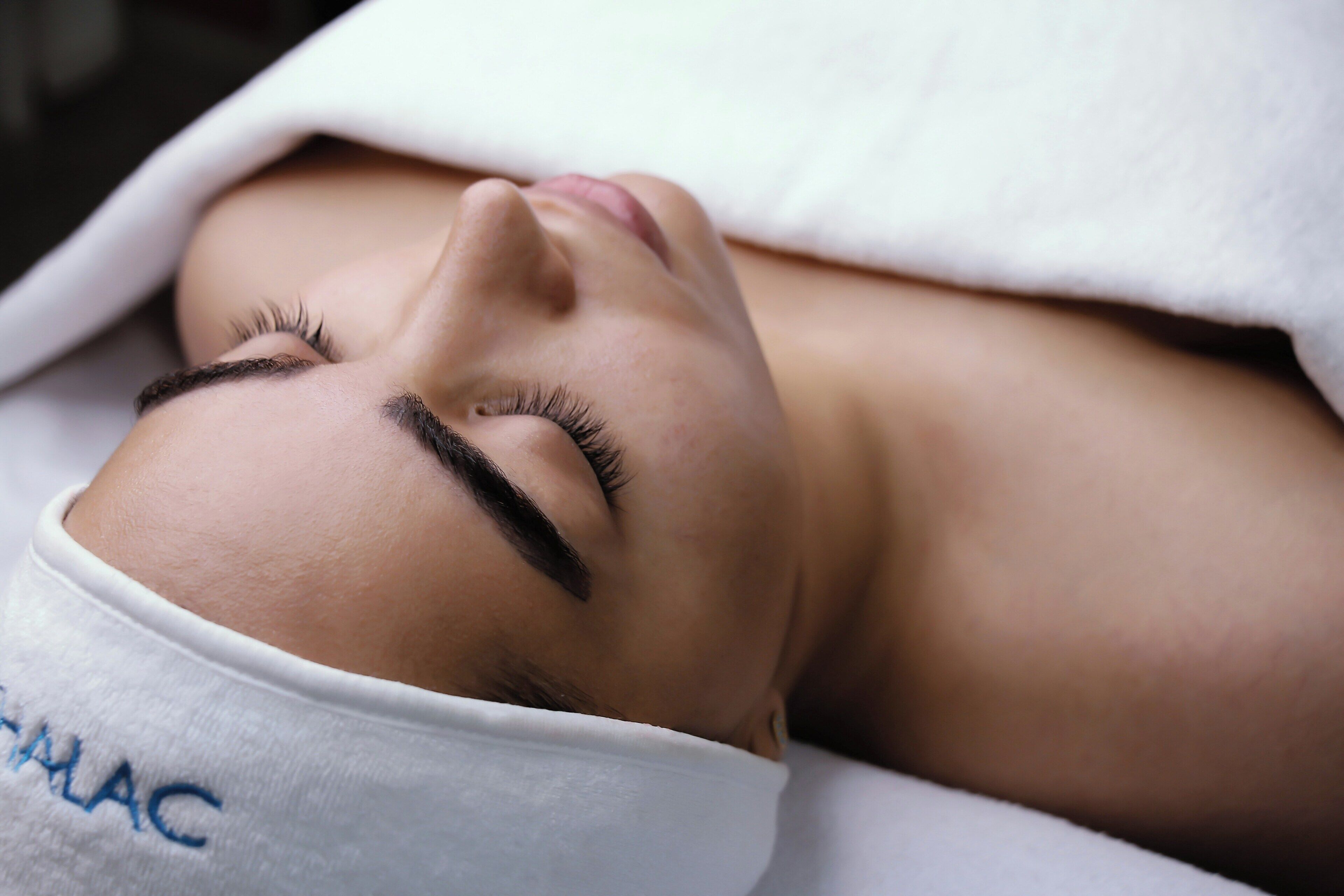 A person lying down with a white towel covering their head.