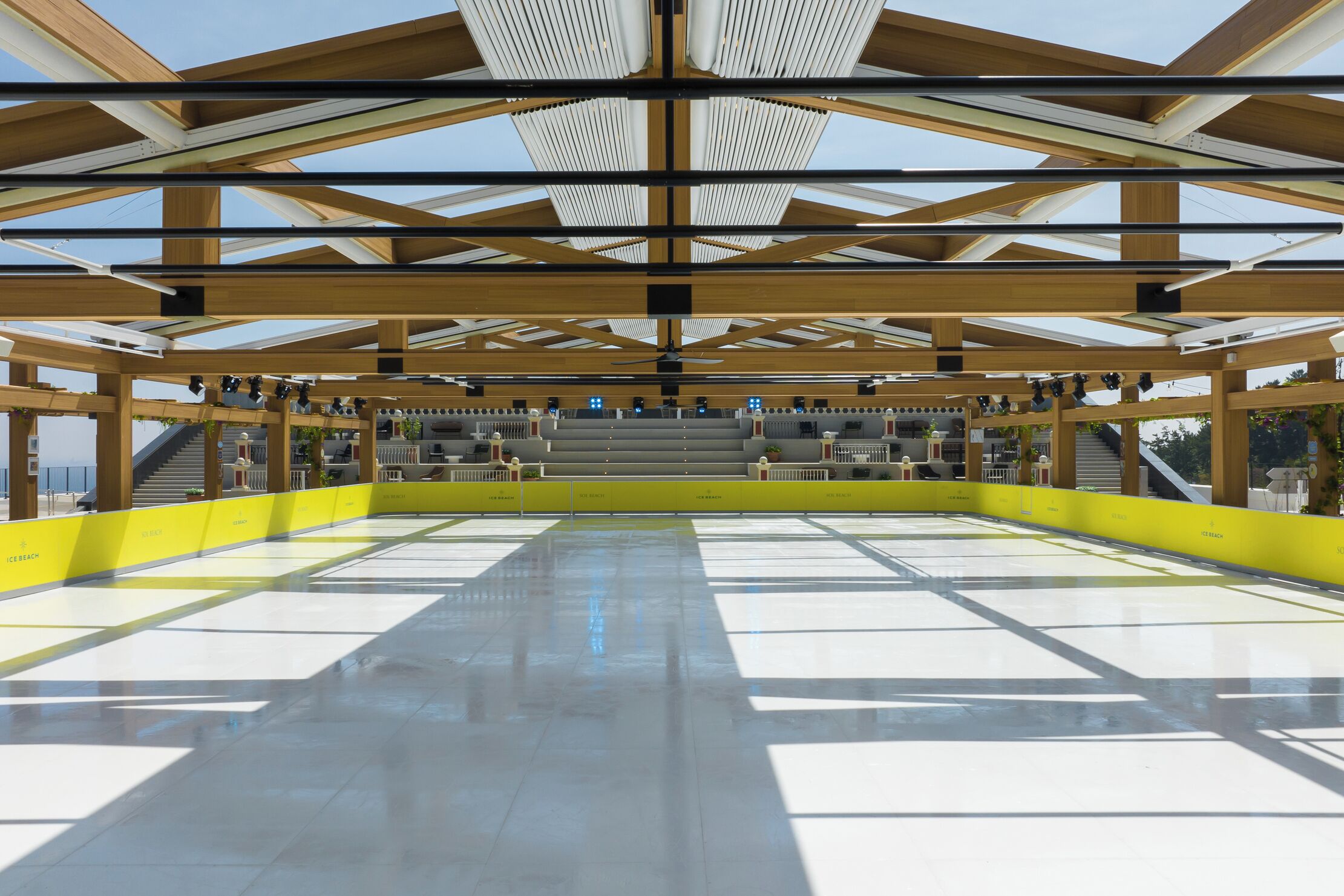 A spacious indoor area with a high ceiling, wooden beams, and a central staircase.