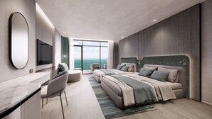 Une chambre moderne dotée d’un grand lit, d’un bureau et d’une télévision. Elle dispose d’une grande fenêtre offrant une vue sur l’océan.