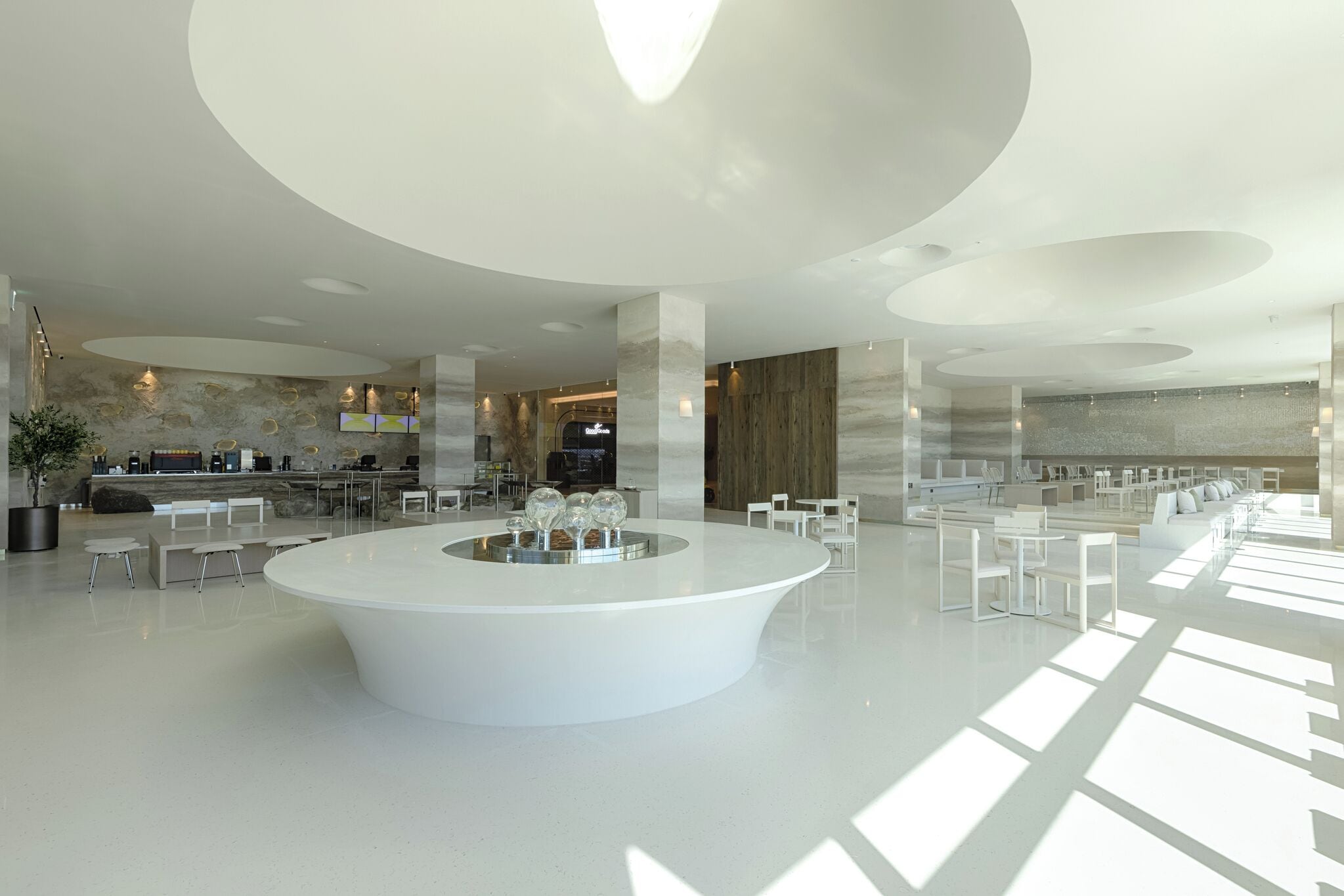 A spacious lobby with a central white reception area, seating arrangements, and a modern architectural design.