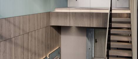 A modern interior with a wooden staircase, a small seating area, and a view of a cityscape.