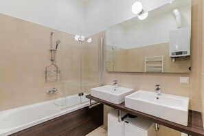 Uma casa de banho moderna com duas pias, cabine de duche envidraçada e um espelho grande.