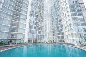 A modern high-rise building with a large swimming pool in front. - ROKET ROOM Majestic By Reccoma (Gading Serpong)