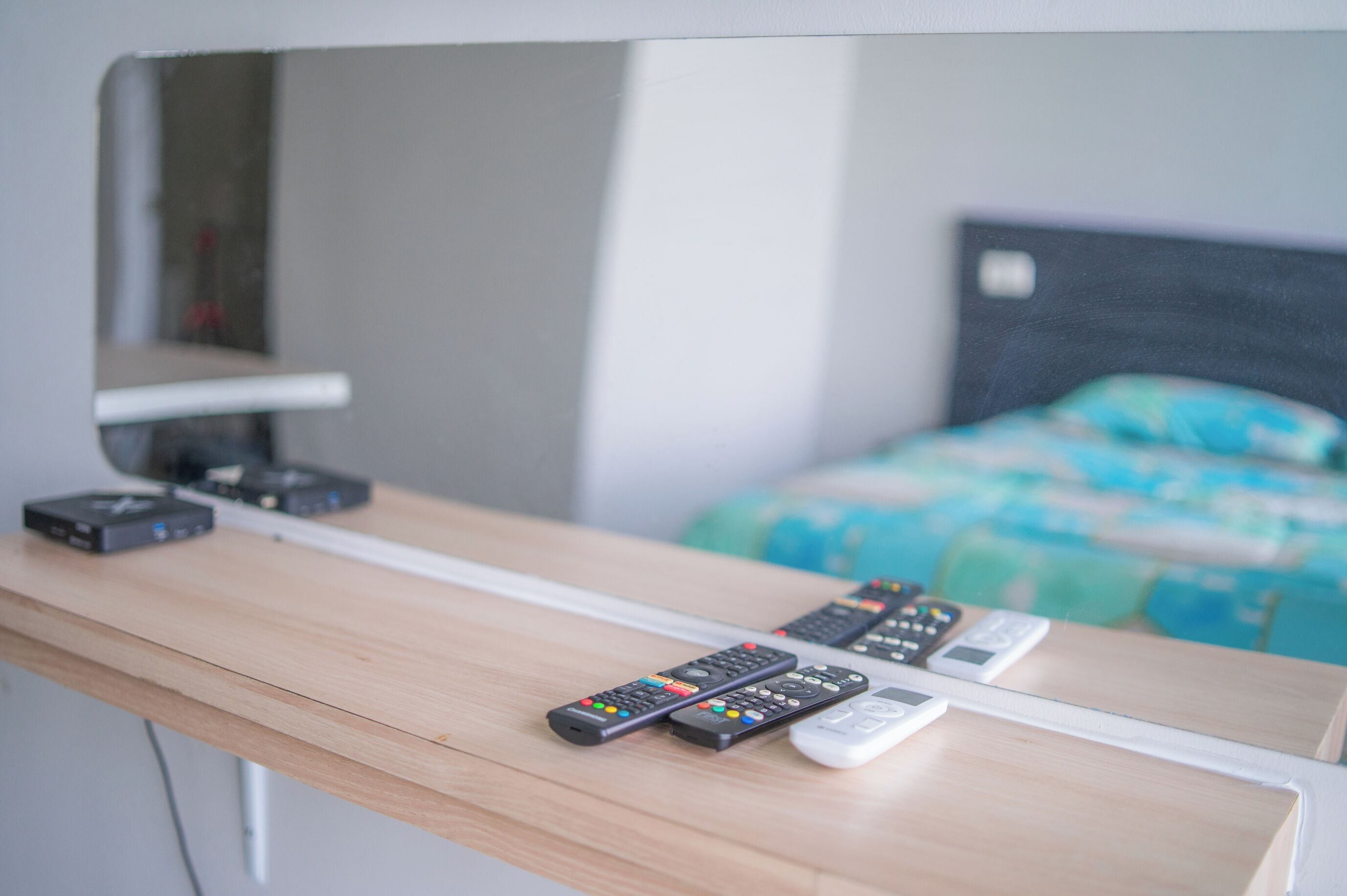 Un escritorio de madera con varios controles remotos y un cable blanco.