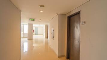 A clean, well-lit hallway with a polished floor, a door with a number plate, and an exit sign.
