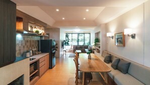 A modern kitchen with wooden cabinets, a dining area with a wooden table and chairs, and a seating area with a sofa.