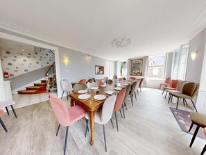 Un coin repas avec une table en bois dressée pour six personnes, entourée de chaises aux pieds noirs et rouges.