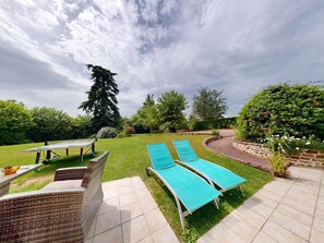 Une terrasse avec deux chaises longues, une table et une piscine.