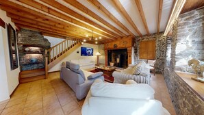 Una sala de estar acogedora con chimenea de piedra, vigas de madera y pared de piedra.