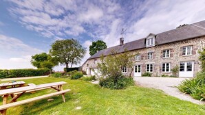 A stone building with a grassy yard and picnic tables. - La Longère 1750 30pers Hambye, piscine grand jardin (Hambye)