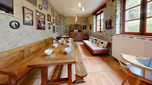 A rustic dining area with a long wooden table, benches, and a stone wall. - La Longère 1750 30pers Hambye, piscine grand jardin (Hambye)