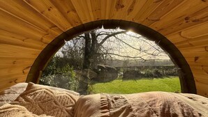A cozy, circular wooden room with a bed and a view of a grassy landscape through a large arched window. - La Longère 1750 30pers Hambye, piscine grand jardin (Hambye)