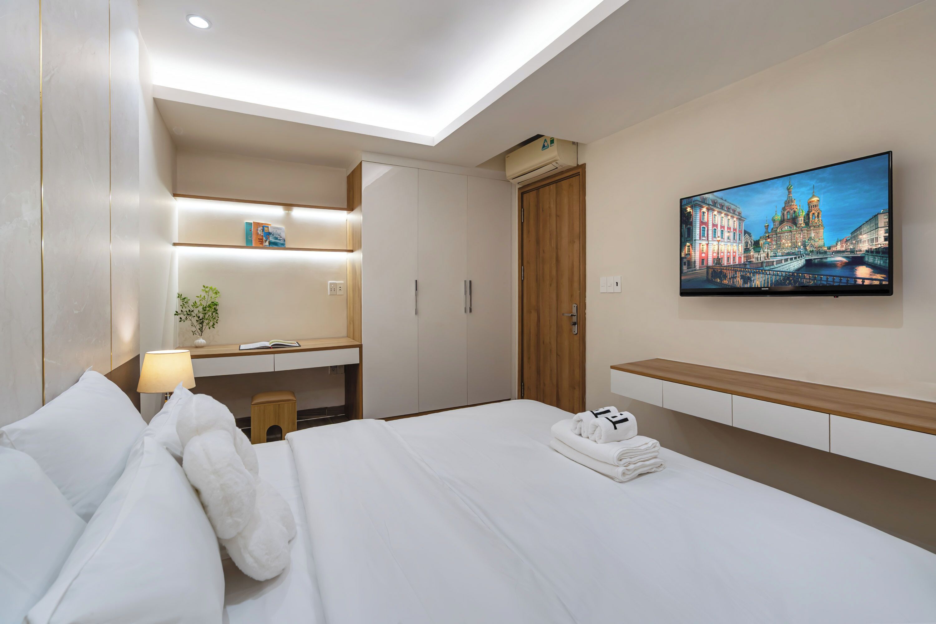 Ein Hotelzimmer mit Bett, Schreibtisch, Fernseher und einem Stadtbild.