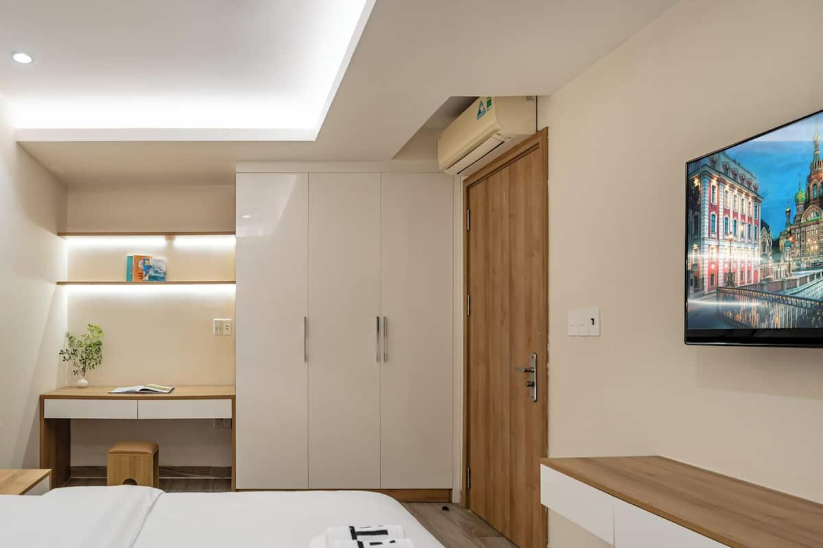 A hotel room with a bed, a desk, a chair, a TV, and a wardrobe.