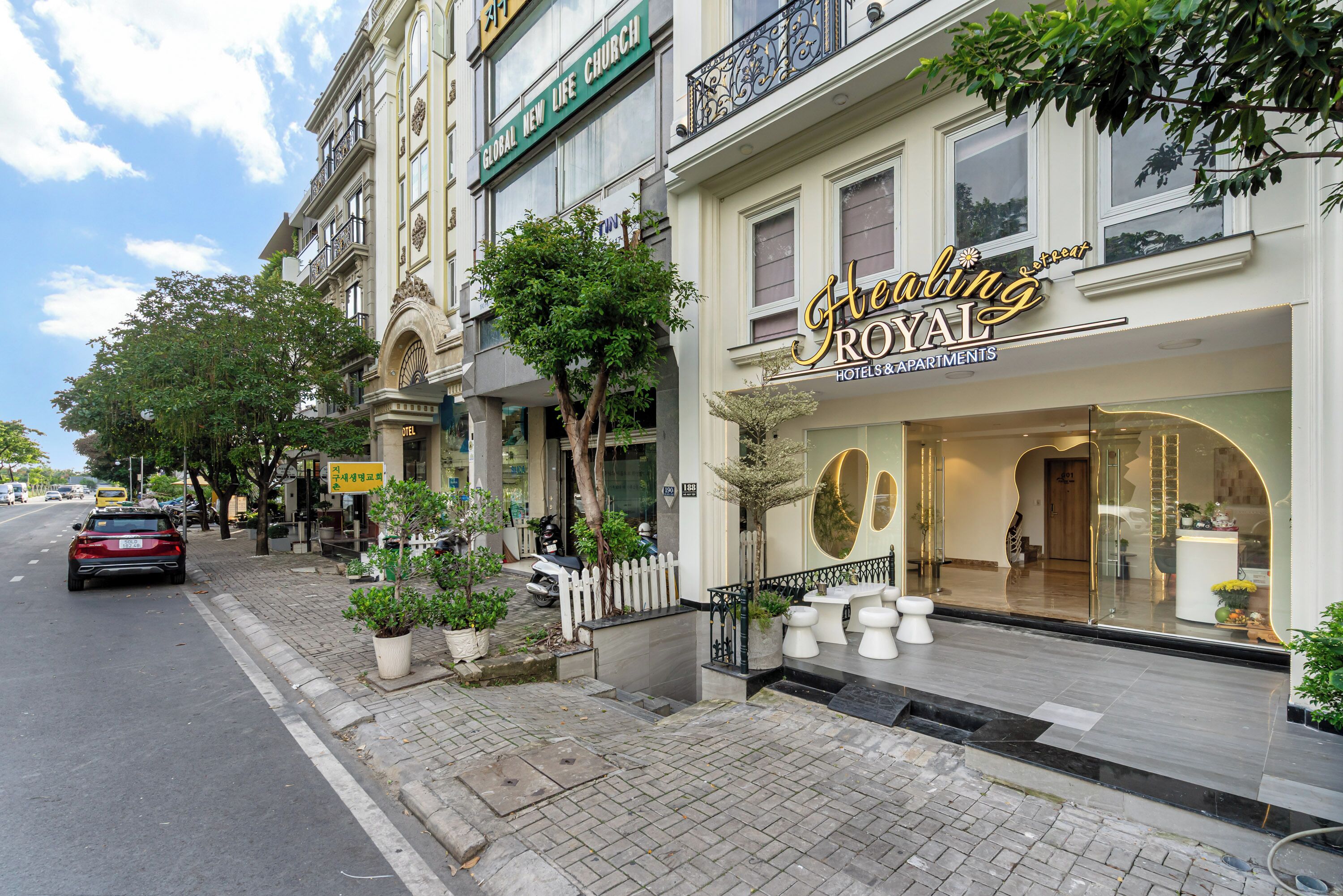 A hotel named "Healing Royal" with a classic architectural style, featuring a prominent entrance and a well-maintained outdoor area with potted plants.