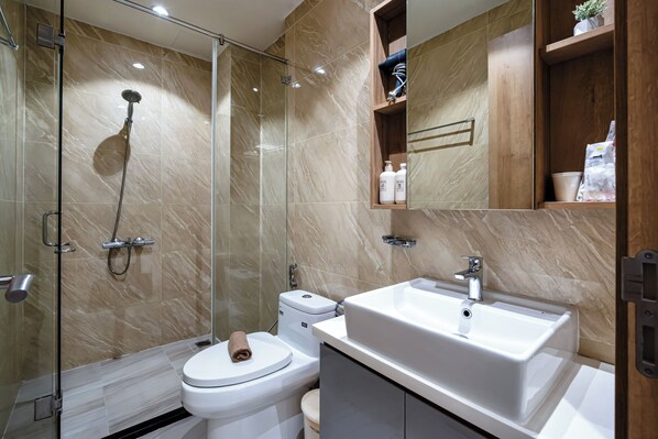 A modern bathroom with a glass-enclosed shower, a white toilet, and a sink with a mirror above it.