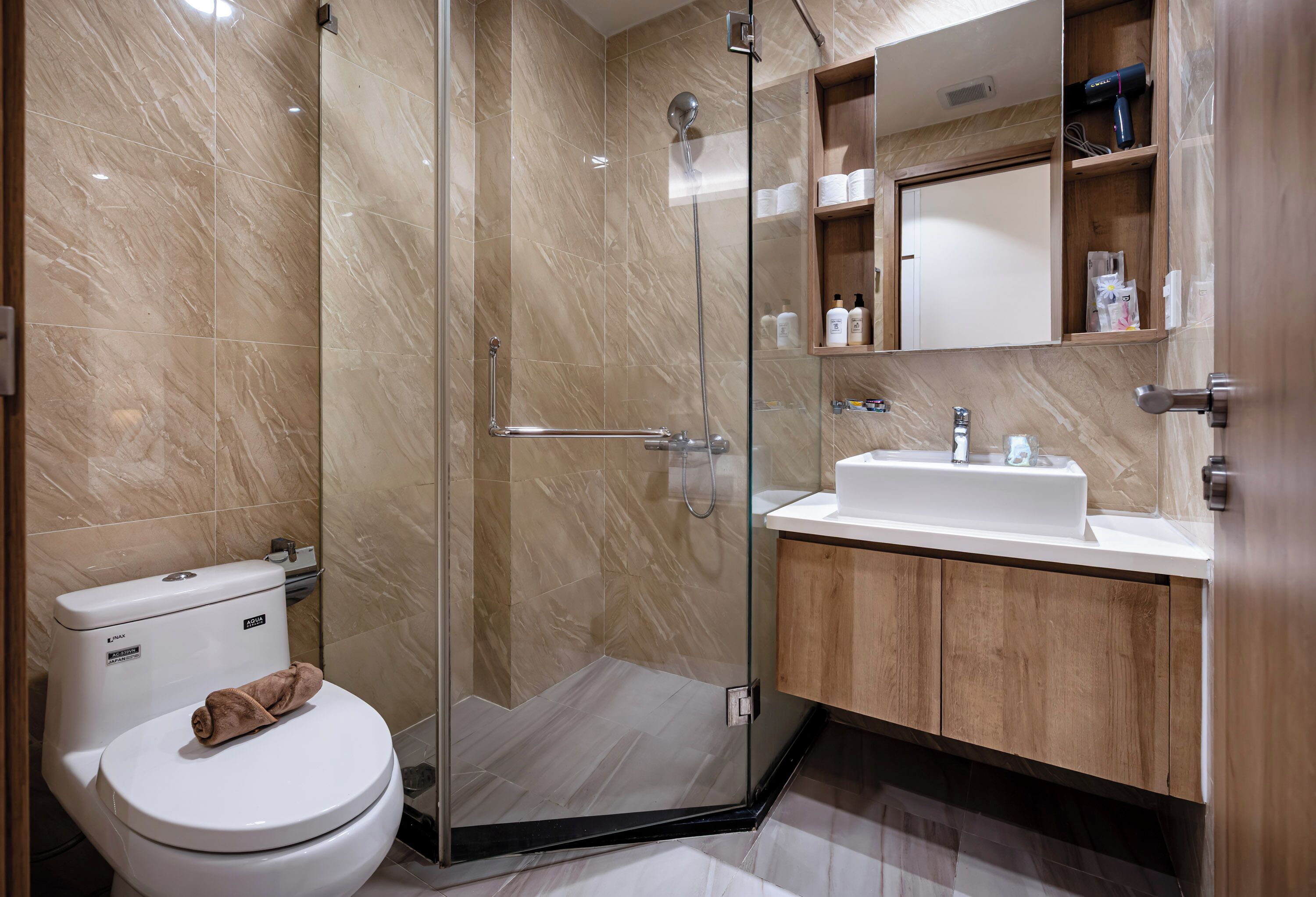 A modern bathroom with a glass-enclosed shower, a white toilet, and wooden cabinets.