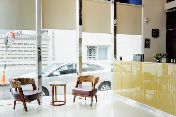 A modern reception area with two wicker chairs, a small table, and a yellow partition. - PP Hotel by Moxy (George Town)