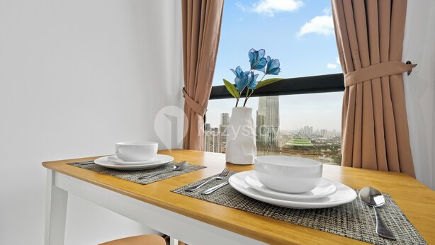 A dining table set with white bowls, silverware, and a vase with blue flowers. - Sano by Kozystay - Sudirman (Jakarta)