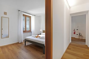 Un dormitorio con cama, ventana con cortinas, mesita de noche y radiador.