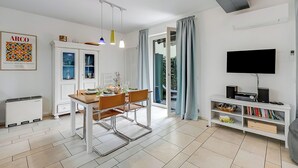Un salon moderne comprenant un coin repas, un téléviseur à écran plat et une bibliothèque.