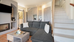 A modern living room with a gray sofa, a coffee table, a flat-screen TV, and a fireplace.