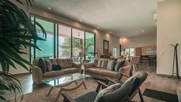 A spacious living room with a large glass coffee table, leather sofas, and a view of the outdoors through large windows. - Quinta Esmeralda (Santiago,)