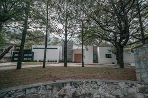 Edifici modern amb mur de pedra i arbres al davant.