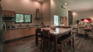 A modern kitchen with wooden cabinets, a granite countertop, and a dining area with a marble table and chairs. - Quinta Esmeralda (Santiago,)