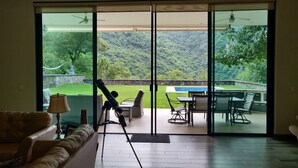 A room with a sliding glass door leading to an outdoor patio with a pool, chairs, and a table. - Quinta Esmeralda (Santiago,)