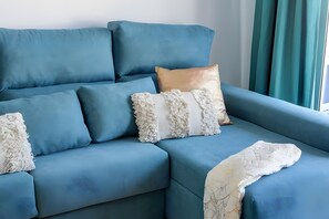 Ein blaues Sofa mit vielen Kissen und einer Decke.