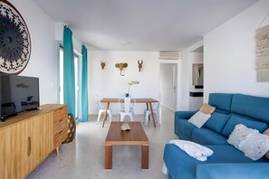 Ein modernes Wohnzimmer mit einem blauen Sofa, einem Holztisch und einem Fernseher auf einer Holzkommode.
