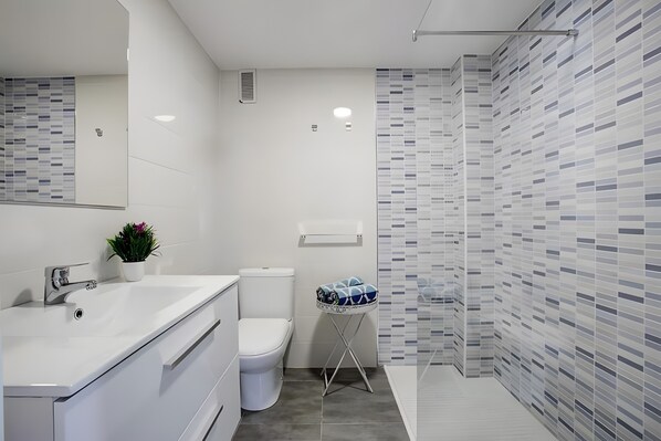 A modern bathroom with a white sink, toilet, and shower.