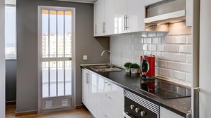 A modern kitchen with white cabinets, a black countertop, a built-in oven, and a red washing machine. - 'Terrazas Playa Gandia' Apartment with Sea View, Wi-Fi and Air Conditioning (Grau i Platja)