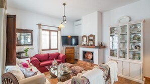 A living room with a red sofa, a television, a fireplace, and a cabinet with dishes. - Holiday Home 'Pozo Viejo' with Private Pool, Wi-Fi and Air Conditioning (Marchena)