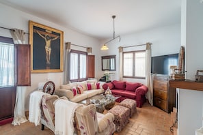 A living room with a wooden coffee table, two sofas, a television, and a crucifix on the wall. - Holiday Home 'Pozo Viejo' with Private Pool, Wi-Fi and Air Conditioning (Marchena)