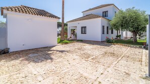 A white building with a tiled roof, a paved courtyard, and a palm tree. - Holiday Home 'Pozo Viejo' with Private Pool, Wi-Fi and Air Conditioning (Marchena)