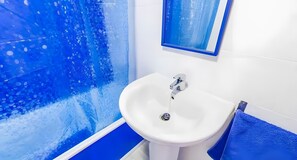 A bathroom with a white sink, a blue shower wall, and a blue towel.