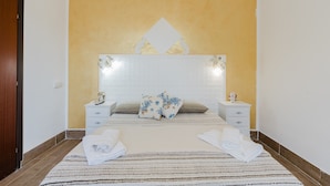 A bedroom with a bed, two bedside tables, a nightstand, a mirror, and a wall with a geometric pattern. - Apartment 'Maresol' with Private Terrace, Wi-Fi and Air Conditioning (Marsala)