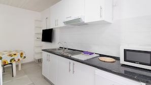 A modern kitchen with white cabinets, a black countertop, a microwave, and a sink.