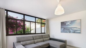 A modern living room with a sectional sofa, a large window with curtains, a pendant light, and a framed picture on the wall.