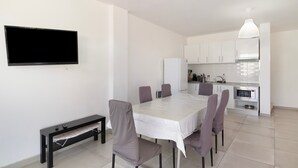 Una cocina moderna con armarios blancos, horno empotrado y un comedor con mesa y sillas.