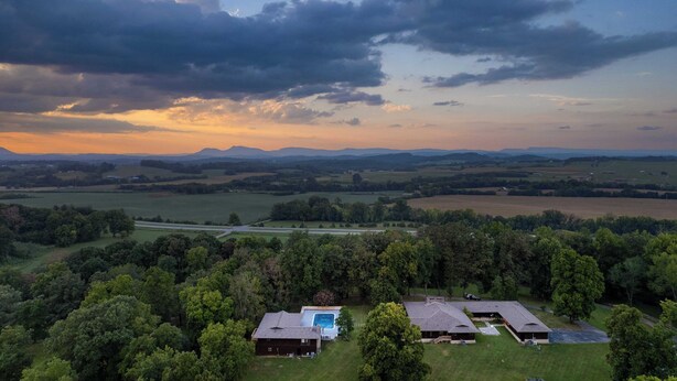 A rural landscape with a large house featuring a swimming pool, multiple barns, and expansive fields. - Amber Cabin by Avantstay Cozy Mountain Retreat (New Market)