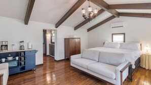 A bedroom with a bed, a sofa, wooden beams, a chandelier, and a kitchenette. - Amber Cabin by Avantstay Cozy Mountain Retreat (New Market)