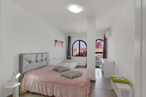 A bedroom with a bed, bedside table, and a view of the outside.