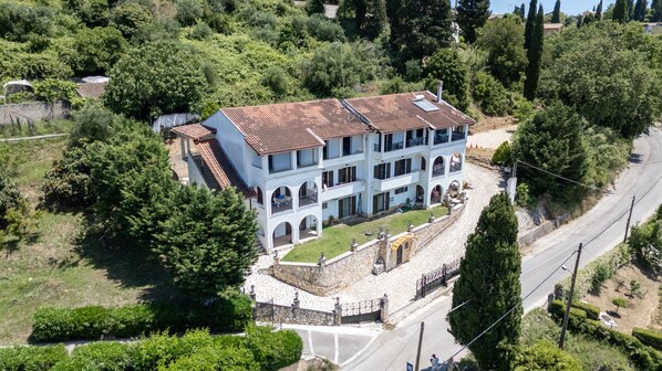 A multi-story building with a tiled roof, surrounded by greenery and a stone wall. - Apartment 'Breathing' with Mountain View, Wi-Fi, and Air Conditioning (Virós)